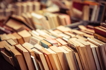 Bücherflohmarkt Ein Haufen Bücher liegt chaotisch auf einem Tisch. Die Cover sind teilweise sichtbar, und die Seiten sind unterschiedlich dick.