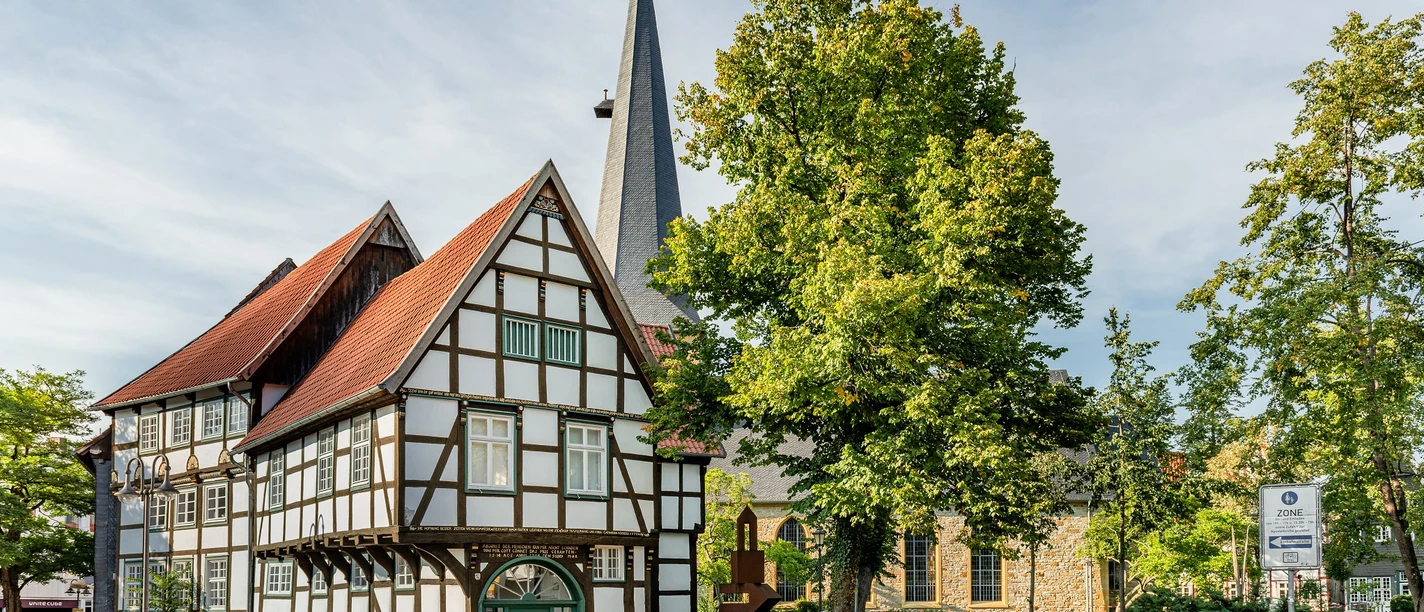 Verhoffhaus © pro Wirtschaft GT, M. Wallenfang, CC BY-SA.jpg Weißes Fachwerkhaus Verhoffhaus mit rotem Dach, Kirchturm und grünen Bäumen.