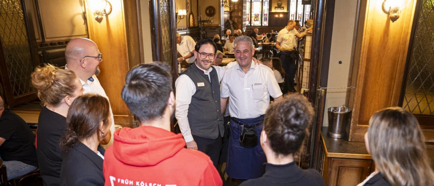 A group on a brewery tour at FRÜH am Dom with two employees in the dining area