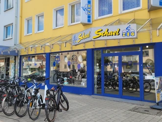 Außenansicht Zweirad Schael Fahrräder vor dem gelb-blauen Eingang des Fahrradgeschäfts Zweirad Schael.