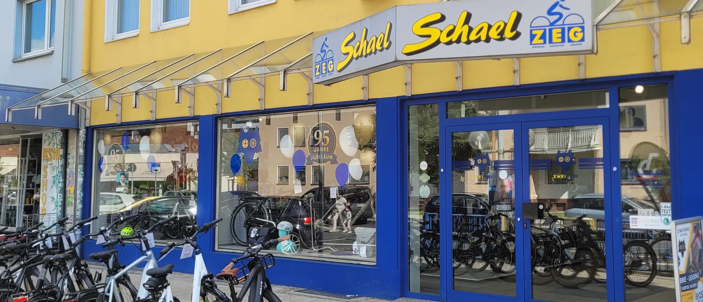 Außenansicht Zweirad Schael Fahrräder vor dem gelb-blauen Eingang des Fahrradgeschäfts Zweirad Schael.
