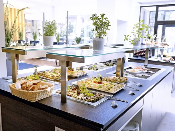 Buffet im Schlosshotel Bad Wilhelmshöhe Ein Buffet Tisch mit mehreren Gerichten ist zu sehen. Im Hintergrund wird der Raum durch die Glasfront erhellt.