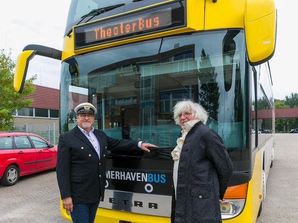Zwei Männer vor einem gelben Theaterbus, einer mit Kapitänsmütze, einer historisch gekleidet.