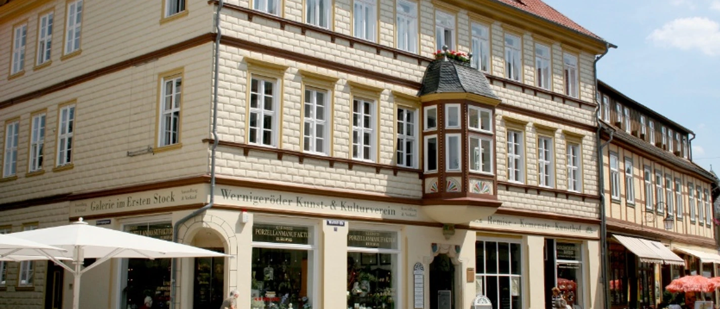 Ein helles Fachwerkhaus mit rotem Ziegeldach in der Innenstadt von Wernigerode. Im Erdgeschoss befindet sich das Geschäft Arezzo Mediterran.