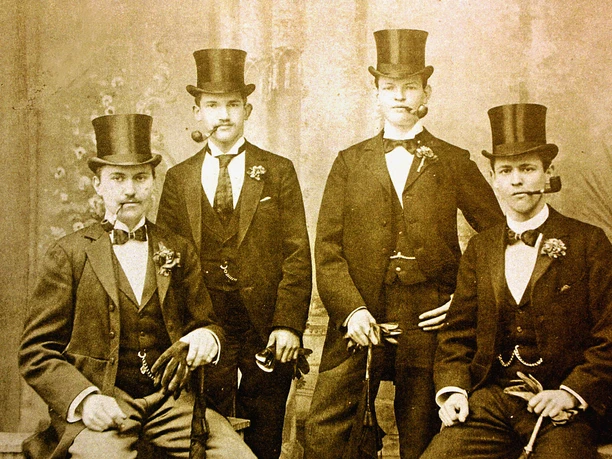 Historisches Sepiafoto: vier Männer mit Zylinder, Anzug und Pfeife.