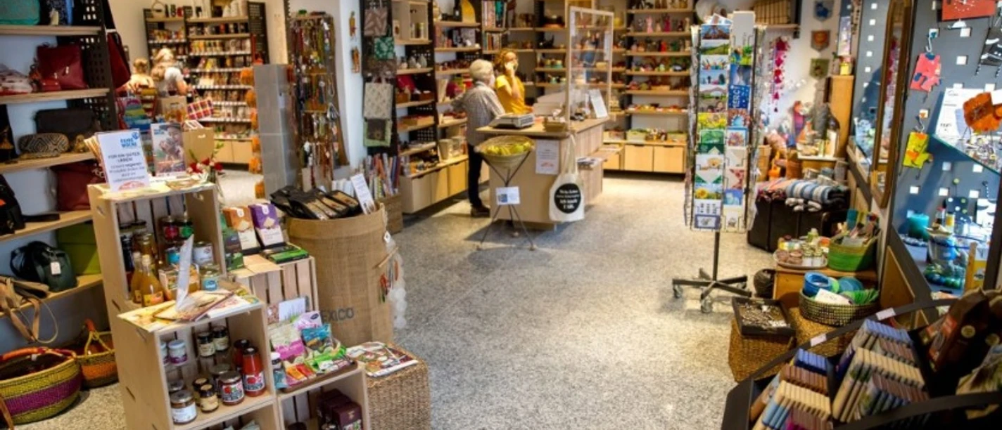 Eine Welt Laden Ein Geschäft mit gefüllten Regalen voller Geschenkartikel, Lebensmitteln und vielen kleinen Produkten.