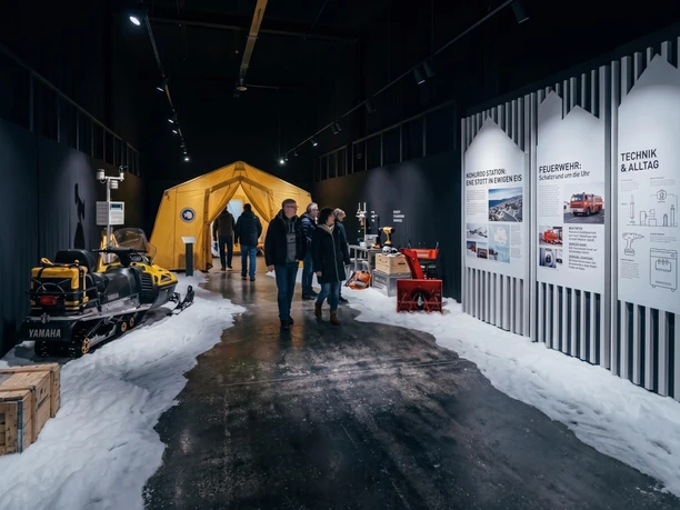 "Polar Worlds" exhibition featuring a snowmobile, an expedition tent, and informational displays in a dark hall