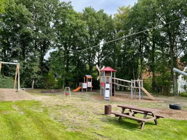 Kinderspielplatz in Stemwede-Destel mit Spielturm, Rutsche, Schaukeln und hölzerner Picknickbank.