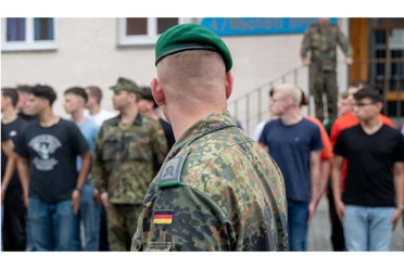 Mann in Bundeswehruniform steht vor Soldaten in Zivil