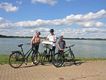 Rast auf der Germanenroute am Alfsee Fahrradfahrer halten an einem See und betrachten gemeinsam eine Landkarte.