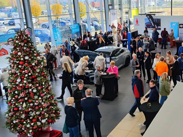 Adventsausstellung im Autohaus mit Weihnachtsbaum, Autos und vielen Gästen.