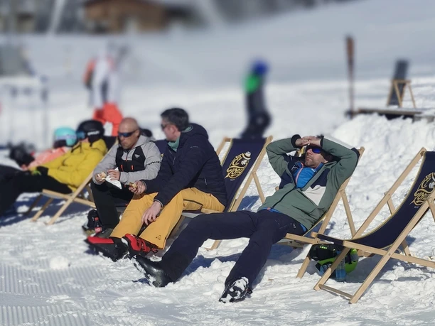 Skiers sit in lounge chairs and enjoy the sun