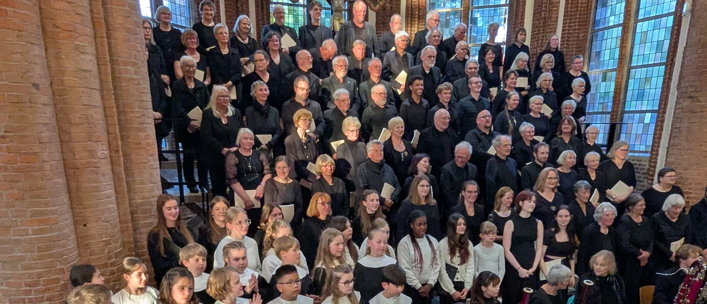 Kinder- und Erwachsenenchor mit Orchester in einer Backsteinkirche.