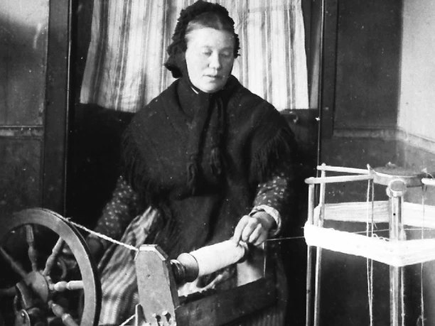 Leinenspinnen- traditionelle Heimarbeit Eine Frau spinnt Leinen an einem alten Spinnrad, umgeben von traditionellen Webutensilien.