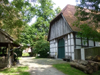 Das Holzhandwerksmuseum Historische Fachwerkscheune im Holzhandwerksmuseum mit umliegenden Bäumen und rustikalen Holzelementen.