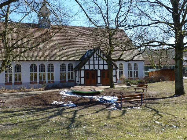 Die evangelische Jugendhilfe Schweicheln Fachwerkgebäude der evangelischen Jugendhilfe Schweicheln, umgeben von Bäumen und Sitzplätzen.