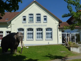 Heimatmuseum Löhne Das Heimatmuseum Löhne präsentiert ein historisches Gebäude mit einem Modell eines Mammuts davor.