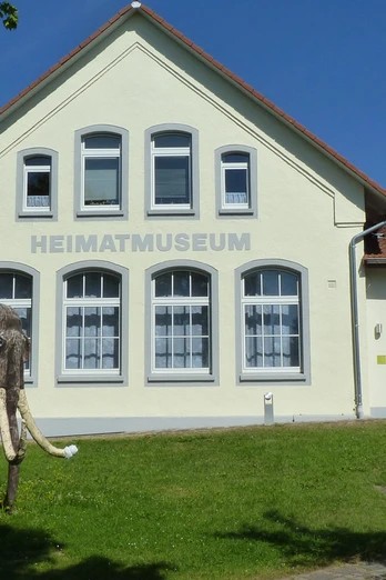 Heimatmuseum Löhne Das Heimatmuseum Löhne präsentiert ein historisches Gebäude mit einem Modell eines Mammuts davor.