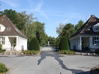 Der Friedhof "Ewiger Frieden" Eingangstor zum "Ewiger Frieden" Friedhof mit zwei symmetrischen Wärterhäuschen und Bäumen.