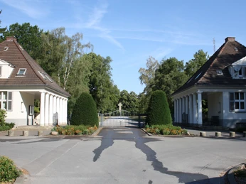 Der Friedhof "Ewiger Frieden" Eingangstor zum "Ewiger Frieden" Friedhof mit zwei symmetrischen Wärterhäuschen und Bäumen.