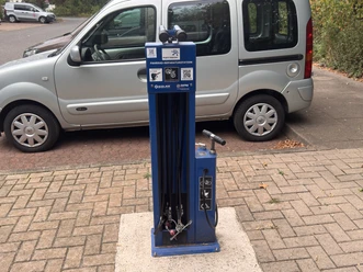 Fahrradreparaturstation Poggenhagen Blaue Fahrrad-Reparaturstation mit Werkzeugen und Pumpe auf Parkplatz.