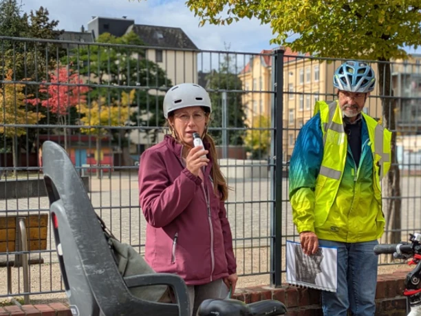 Radführerin mit Mikrofon, Teilnehmer in Warnweste und Fahrräder am Stadtplatz.