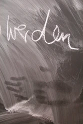 auf einer Tafel steht das Wort "werden" geschrieben, darunter sind Spuren von Händen zu sehen