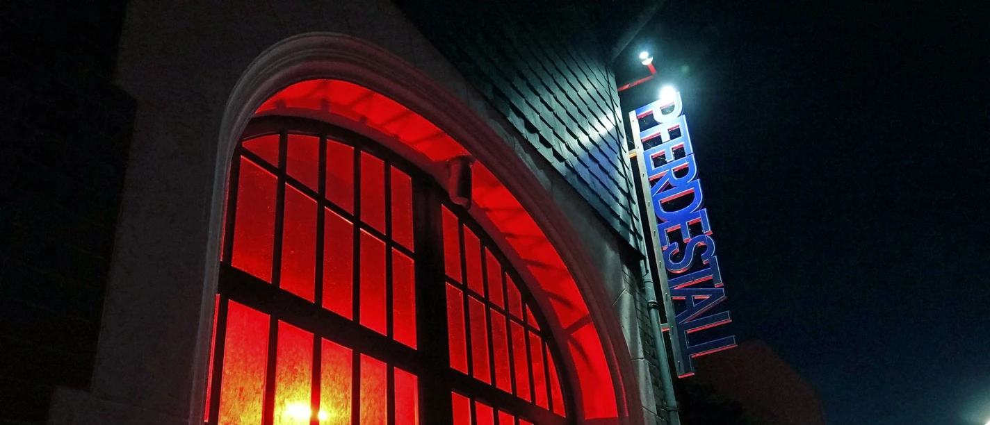 Rot beleuchteter Eingang des Pferdestalls Bremerhaven bei Nacht.