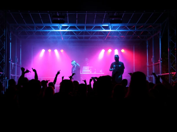 Publikum vor Konzertbühne mit pink-blauem Licht beim United-We-Stand-Festival.