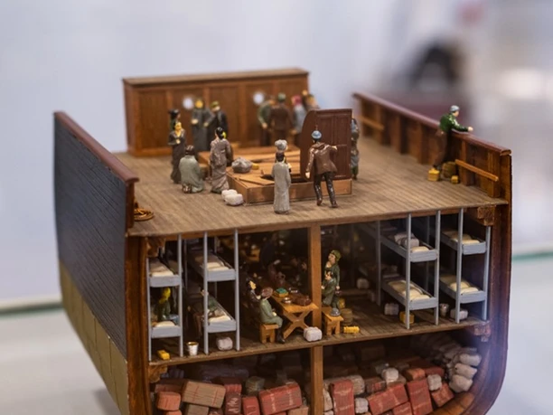 Detailreiches Schnittmodell eines Schiffs mit Figuren, Kojen und gestapelter Ladung.