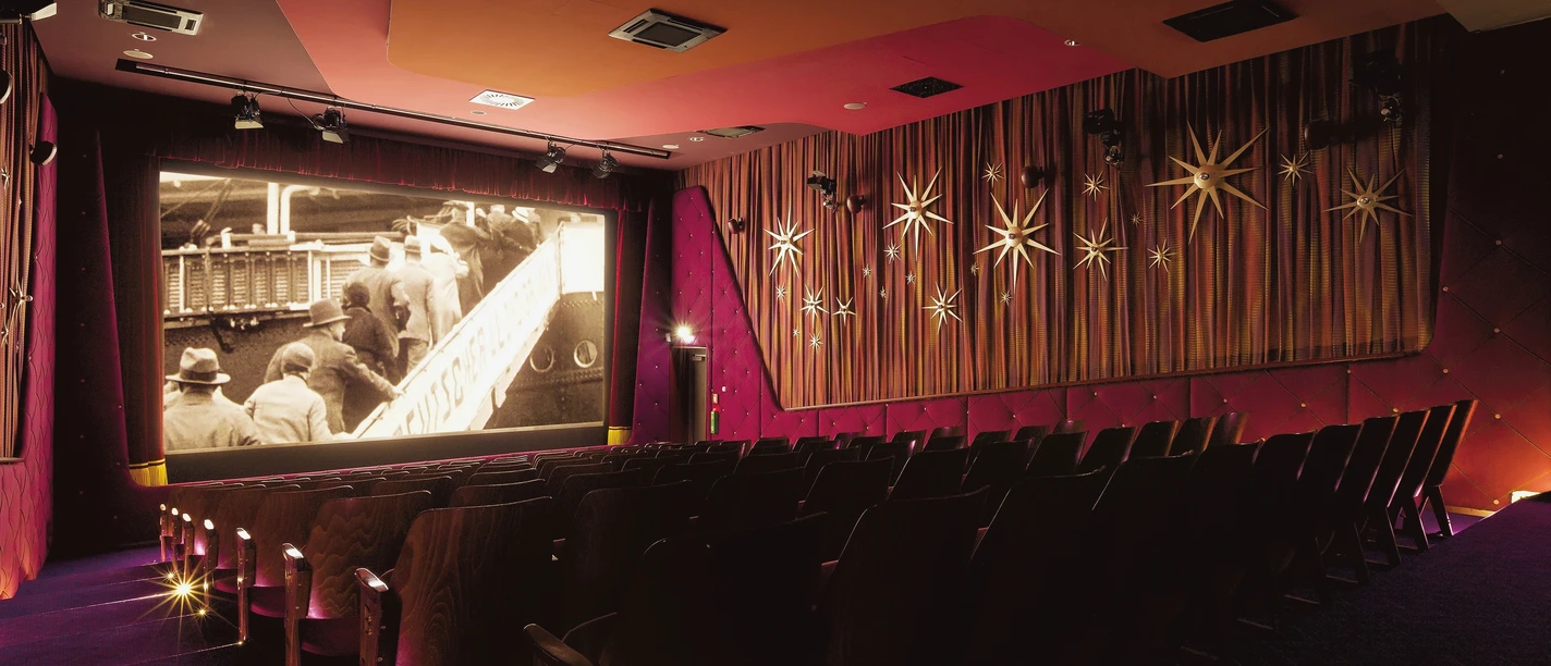 Kinosaal im Deutschen Auswandererhaus mit Leinwand, roten Wänden und Sternendekor.