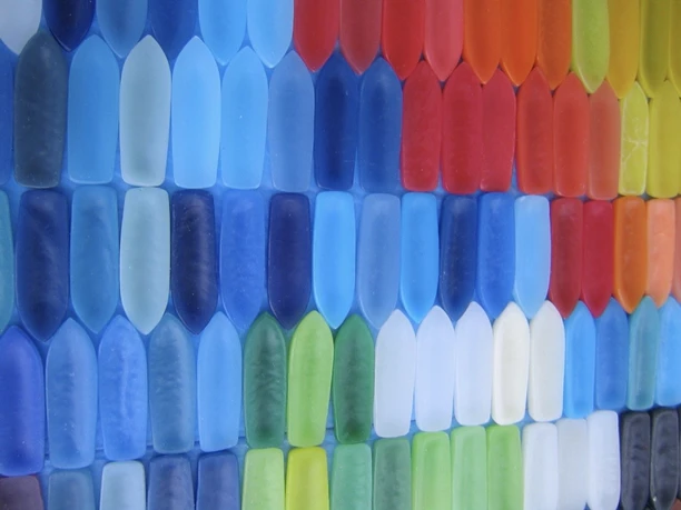 Bunte Wachsschiffchen in Reihen, von Blau über Rot bis Grün und Weiß.