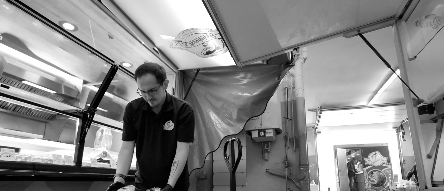 Mobiler Fischhändler sortiert Fische in Styroporboxen im Verkaufswagen.