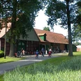 Das Heimatmueseum am Hühnermoor in Marienfeld Eine Gruppe von Radfahrern vor einem großen roten Backsteingebäude in einer grünen Landschaft.