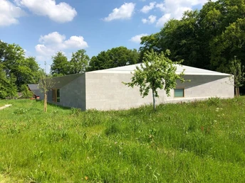 Museum Peter August Böckstiegel Modernes Gebäude mit schrägem Dach in natürlicher Landschaft, umgeben von grüner Wiese und Bäumen.