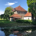 Bürgerbegegnungsstätte Haus Werther Historisches Gebäude mit roten Ziegeldächern am Ufer eines Wassergrabens, umgeben von Bäumen.