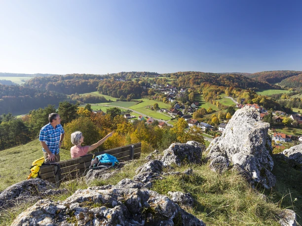 Am Alpinen Steig Ein Ehepaar auf dem Alpinen Steig macht Rast bei einer Ruhebank. Im Hintergrund hat meinen einen schönen Weitblick auf den Ort Schönhofen und die Juralandschaft.