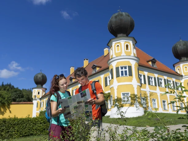 Schloss Ramspau Zwei Personen mit Karte vor dem gelben Schloss Ramspau, blauer Himmel.