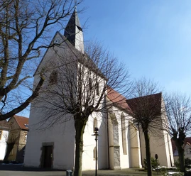 Evangelische Kirche Borgholzhausen Historische Kirche mit weißem Putz und rotem Dach, von kahlen Bäumen umgeben, unter blauem Himmel.