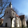 Evangelische Kirche Borgholzhausen Historische Kirche mit weißem Putz und rotem Dach, von kahlen Bäumen umgeben, unter blauem Himmel.