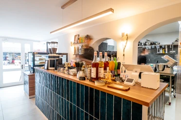 Theke im Café Ne.Na Theke im NE.NA Café mit Kaffeemühle, Sirupflaschen und Blick in die offene Küche