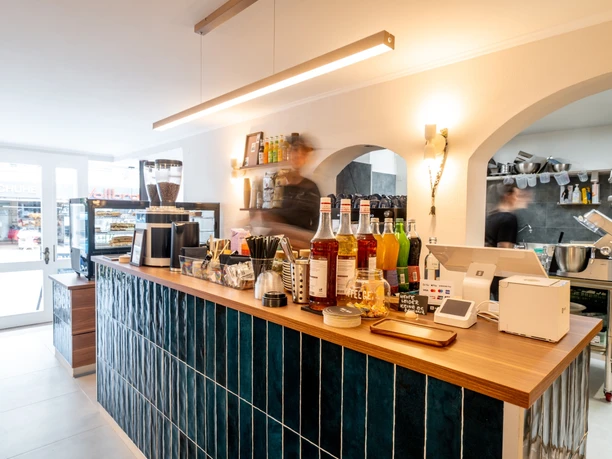Theke im Café Ne.Na Theke im NE.NA Café mit Kaffeemühle, Sirupflaschen und Blick in die offene Küche