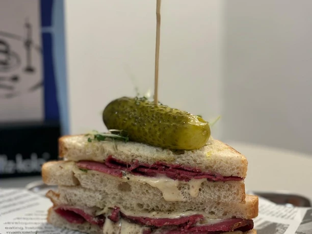 Sandwich im Café Ne.Na Sandwich mit Pastrami, Käse und Gewürzgurke auf Tablett im NE.NA Café