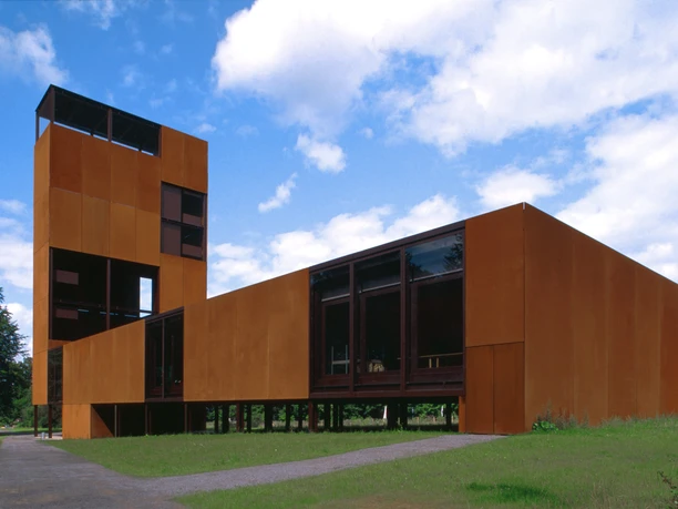 Varusschlacht im Osnabrücker Land - Museum und Park Kalkriese Modernes Gebäude aus rostfarbenem Stahl mit großen Fenstern und einem hohen Turm unter blauem Himmel.