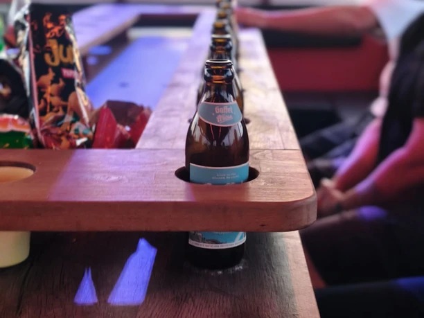 Wolle's Eventfahrten Bierflaschen in einer Holztheke während einer Planwagenfahrt mit Gästen im Hintergrund