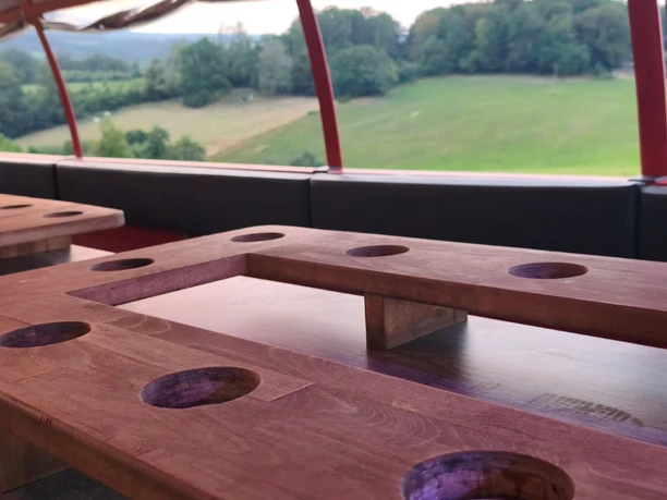 Wolle's Eventfahrten Holztische im überdachten Planwagen mit Blick auf grüne Felder und Wald.