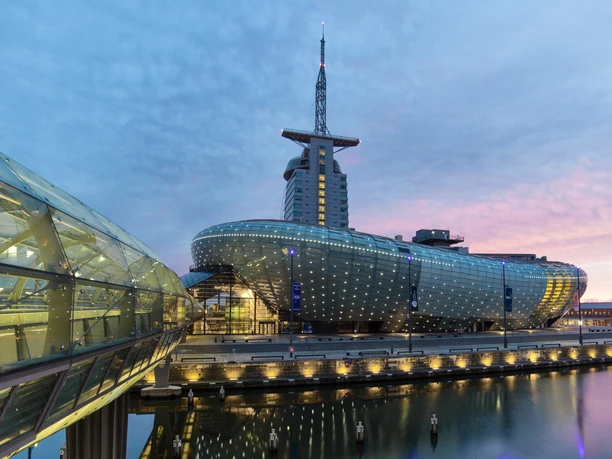 Deutsches Auswandererhaus, Klimahaus Bremerhaven Klimahaus Bremerhaven mit beleuchteter Glasfassade am Hafen in der Abenddämmerung.
