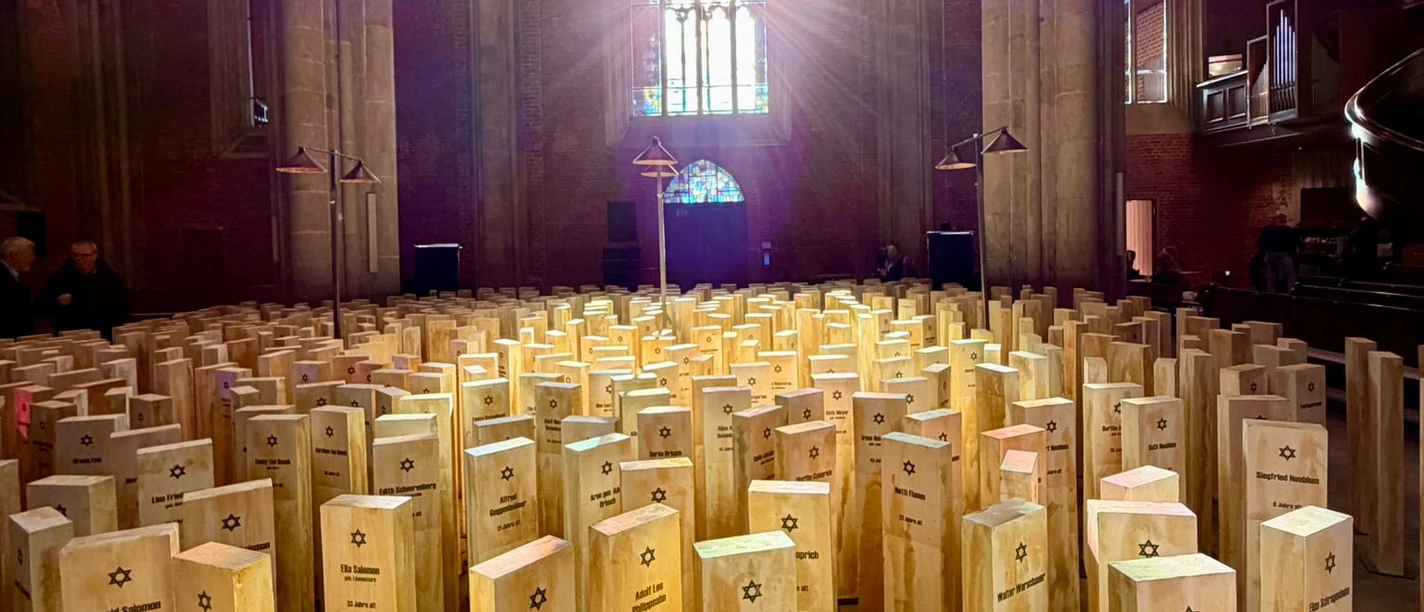 Spuren des Erinnerns Gedenkinstallation mit Holzstelen, Namen und Davidsternen unter Kirchengewölben.