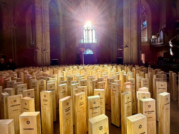 Spuren des Erinnerns Gedenkinstallation mit Holzstelen, Namen und Davidsternen unter Kirchengewölben.