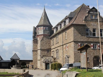 Burg Schwalenberg aus Stein mit markantem Turm und Fachwerk-Elementen, umgeben von Wolken.